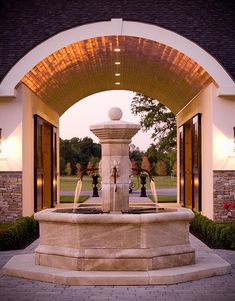 the entrance to a building with a fountain in it's center and lights on either side