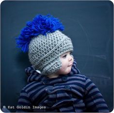 a small child wearing a knitted hat with blue pom - poms