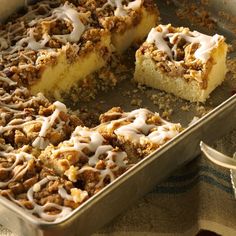 a pan filled with cake covered in icing next to a slice of cake on top of a table