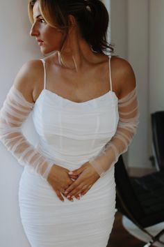 a woman in a white dress posing for the camera with her hands on her hips