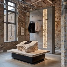 a stone bench in front of a brick wall with clothes hanging on it and two windows