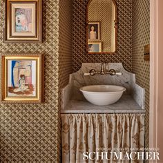 a bathroom sink sitting under a mirror next to pictures on the wall and in front of it