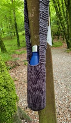 a purple knitted bag hanging from a tree in the middle of a wooded area