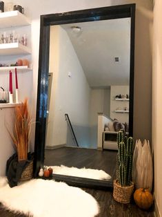 a mirror sitting on top of a wooden floor next to a shelf filled with vases