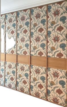 a room divider made out of wood and fabric with flowers on the wall behind it