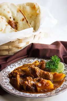 a plate with some food on it next to bread and a basket filled with tortillas