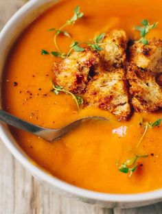 a white bowl filled with tomato soup and bread croutons on top of it