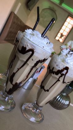 two glasses filled with ice cream and toppings on top of a table next to each other