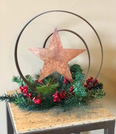 a metal star on top of a table with greenery and berries in the center