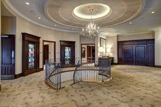 a spiral staircase in the middle of a large room with chandelier above it