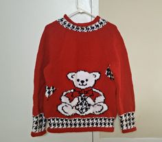 This listing is for a handmade Teddy Bear sweater for newborn babies, toddlers, infants and young kids. Each sweater is 100% knitted by hand and has a beautiful teddy bear design in black, white and red. This jumper can be personalized with initials or names and it can also be customized in terms of its color, pattern, design, measurements, shape, size, material and thickness since I typically purchase new material for each order. You can even choose to have the sweater crocheted instead of knitted.  This adorable sweater is perfect to wear out and keep warm in fall and winter or to gift your loved ones for any special occasion. It is made with 100% acrylic yarn, so I recommend that you machine wash it on gentle cycle or hand wash it with warm water and a gentle detergent. For hand wash, l Cute Red Winter Sweater, Red Hand Knitted Crew Neck Sweater, Red Hand-knitted Sweater, Handmade Red Winter Patterns, Handmade Red Patterns For Winter, Red Hand Knitted Sweater, Teddy Bear Sweater, White Teddy Bear, Winter Jumpers