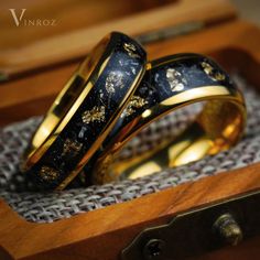 two gold wedding rings sitting on top of a wooden box