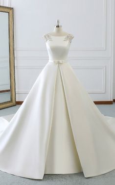 a white wedding dress on display in front of a mirror