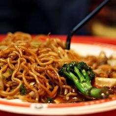 a plate with noodles, broccoli and other food items on top of it