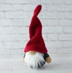 a crocheted red and white gnome hat on top of a small stuffed animal