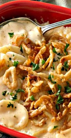 a red bowl filled with pasta and cheese covered in gravy, garnished with parsley