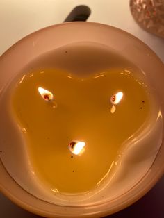 a white bowl filled with liquid on top of a table next to a candle holder