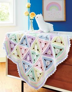 a crocheted blanket on top of a dresser in a room with blue walls