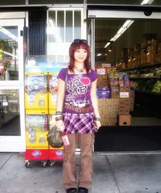 a woman standing in front of a store with her hands in her pockets and purse