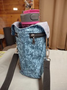 a blue purse sitting on top of a bed next to a pink cell phone holder