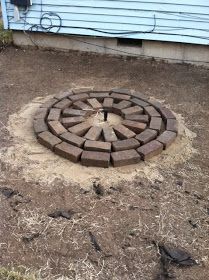 a brick fire pit sitting in the middle of a yard