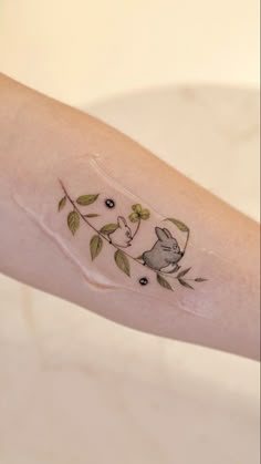 a small tattoo on the arm of a woman with flowers and a cat in it