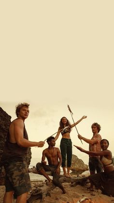 a group of people standing next to each other on top of a rocky hill near the ocean