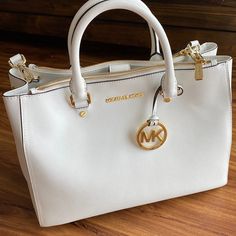 Mk Handbag, Excellent Condition, See Pictures For Details. 100% Authentic. Beautiful Clean White With Gold Details. This Was My Moms Bag And It Needs A Good Home! Gray Bag Also Available As Well As Other Mk Bags, Please Check Them Out! Feel Free To Ask Questions And Offers Welcome! White Shopping Bag With Gold-tone Hardware, White Satchel With Gold-tone Hardware, Michael Kors White Shoulder Bag With Branded Hardware, White Michael Kors Shoulder Bag With Branded Hardware, White Tote Satchel With Gold-tone Hardware, White Shopping Bags With Gold-tone Hardware, White Satchel Tote With Gold-tone Hardware, White Bags With Gold-tone Hardware For Travel, White Tote Bag With Gold-tone Hardware