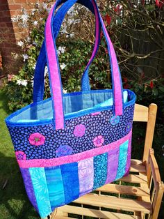 a blue and pink bag sitting on top of a wooden bench