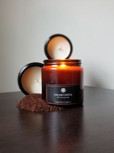 a candle sitting on top of a wooden table next to a jar filled with dirt