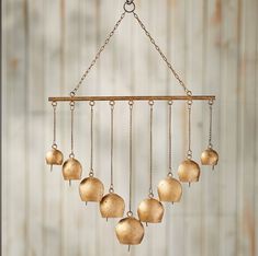 a gold colored wind chime hanging from a metal chain with five bells attached to it