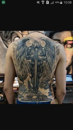 the back of a man's body with tattoos on it and angel wings above his head