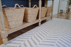 three baskets sitting on top of a wooden shelf next to a white rug in front of a fireplace