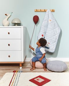 a little boy sitting on the floor playing with a balloon