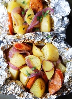 two foil packets filled with potatoes, carrots and other vegetables on top of each other