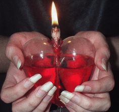 a woman holding a heart shaped candle in her hands with white nails on the fingers