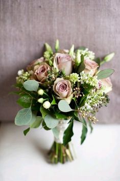 a bouquet of flowers sitting on top of a white table next to a gray couch