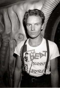 a black and white photo of a man standing in front of an alien creature head