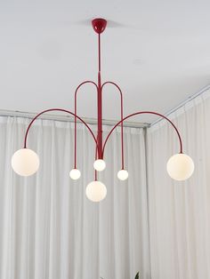 a red chandelier hanging from the ceiling in a room with white drapes