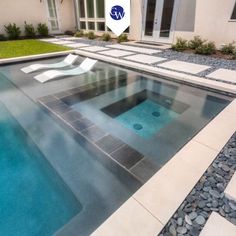 an empty pool in front of a house with stones on the ground and grass around it