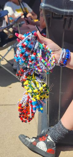 a woman's hand with bracelets hanging from a trash can on the sidewalk