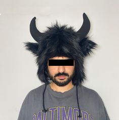 Unleash your inner beast with this Wild Bull Plush Hat! Featuring two plush black horns and soft faux fur, this hat is a playful mix of comfort and character. The unique design includes subtle ear details and a shaggy, black fur texture that makes it stand out at costume parties, festivals, or even casual wear for those daring to make a statement. With adjustable earflaps for added warmth, this hat is perfect for keeping you cozy while letting your adventurous side roam free. Make a bold impress Black Horns, Wild Bull, Winter Headwear, Plush Hat, Fur Texture, Costume Parties, Fur Hat, Costume Party, Halloween Shopping