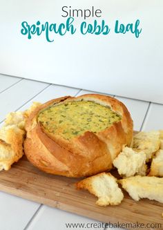 a bread bowl filled with spinach and cheese on a cutting board next to crackers