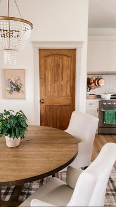 a dining room table with white chairs and a potted plant