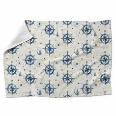 a blue and white blanket with an anchor, wheel and star pattern on it's side