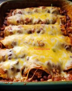 three enchiladas in a green casserole dish with cheese and beans