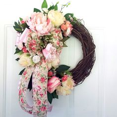 a wreath with pink and white flowers hanging on a door