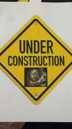 a yellow and black sign that says under construction with a picture of a baby in the center