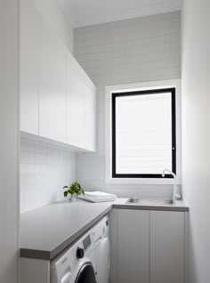 a washer and dryer in a small room with a window above the sink