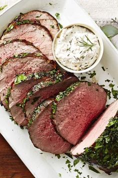 sliced steak with herbs and ranch dressing on a white platter